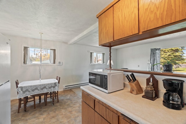 kitchen featuring a textured ceiling, white microwave, a notable chandelier, baseboard heating, and light countertops
