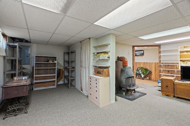 finished below grade area featuring carpet floors, a wood stove, and a drop ceiling