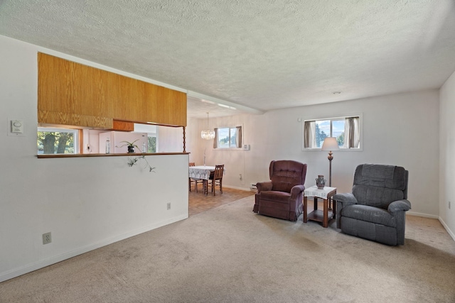 living area with carpet floors, baseboards, a textured ceiling, and a chandelier