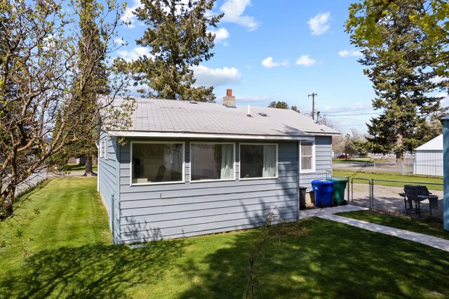 rear view of property with a yard, a chimney, and fence