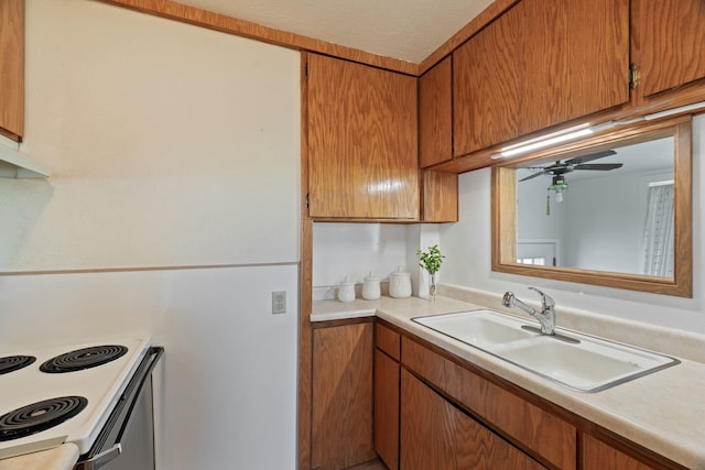 kitchen featuring white range with electric stovetop, a sink, brown cabinets, ceiling fan, and light countertops