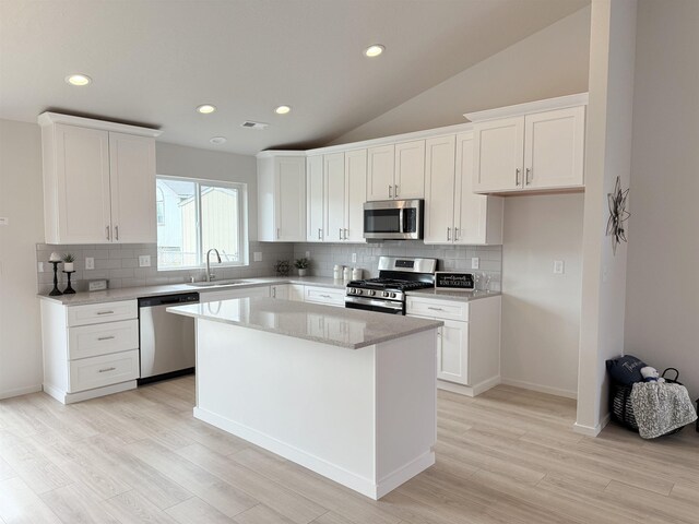 kitchen with backsplash, appliances with stainless steel finishes, a sink, and light wood finished floors