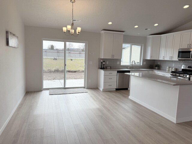 kitchen featuring a sink, decorative backsplash, an inviting chandelier, stainless steel appliances, and white cabinets