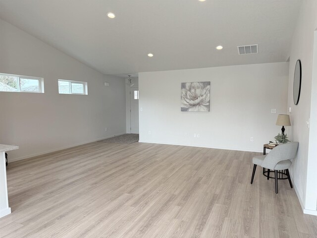 interior space featuring light wood-style floors, baseboards, lofted ceiling, visible vents, and recessed lighting