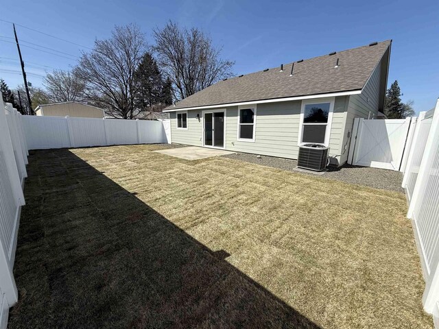 back of property featuring a fenced backyard, a yard, central AC, a patio area, and roof with shingles