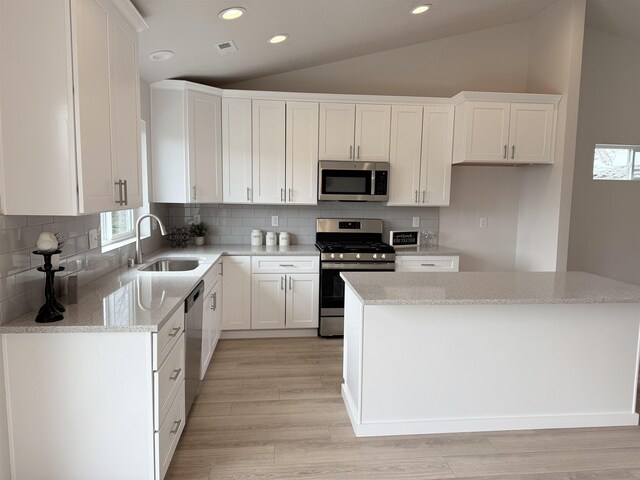 kitchen with a sink, light wood-type flooring, stainless steel appliances, lofted ceiling, and recessed lighting
