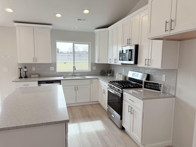 kitchen featuring a sink, white cabinetry, appliances with stainless steel finishes, light stone countertops, and recessed lighting