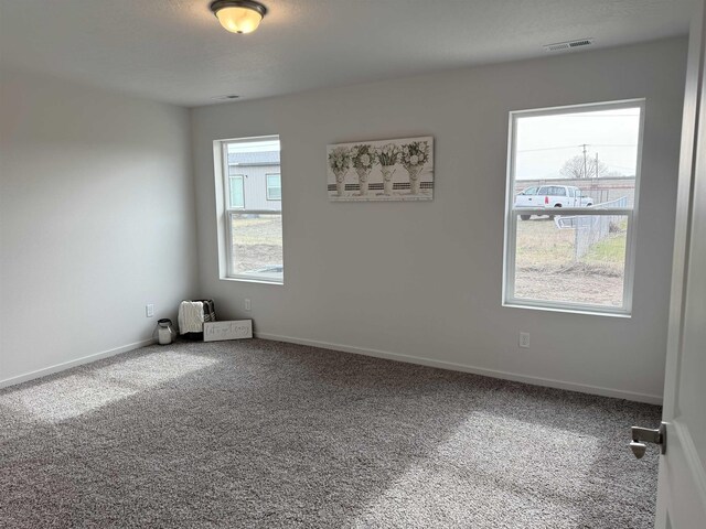 spare room featuring carpet floors, visible vents, and baseboards