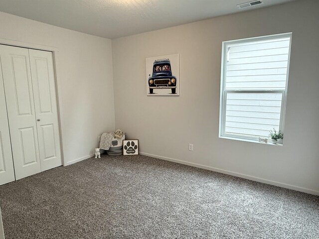 unfurnished bedroom with a closet, visible vents, carpet flooring, and baseboards