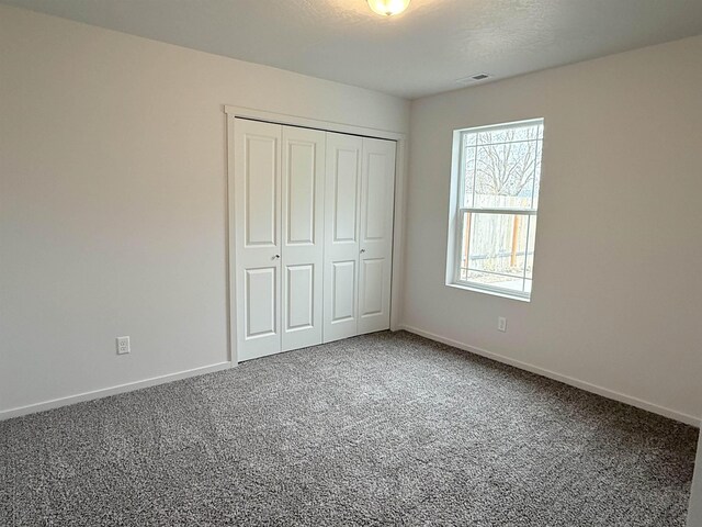 unfurnished bedroom with carpet floors, a closet, visible vents, and baseboards