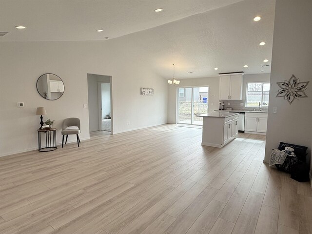living room with recessed lighting, lofted ceiling, a chandelier, and light wood-style flooring