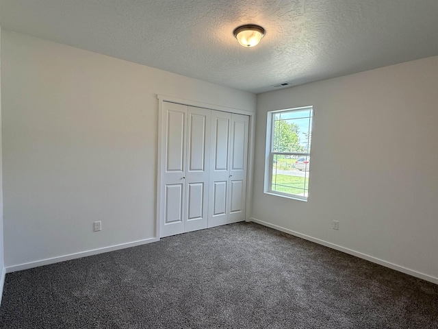 9520 E Michielli Ln, Spokane Valley, WA 99206 - unfurnished bedroom featuring a textured ceiling, dark colored carpet, and a closet
