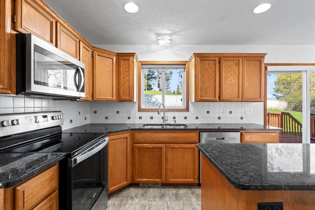kitchen with brown cabinetry, stainless steel appliances, and a sink