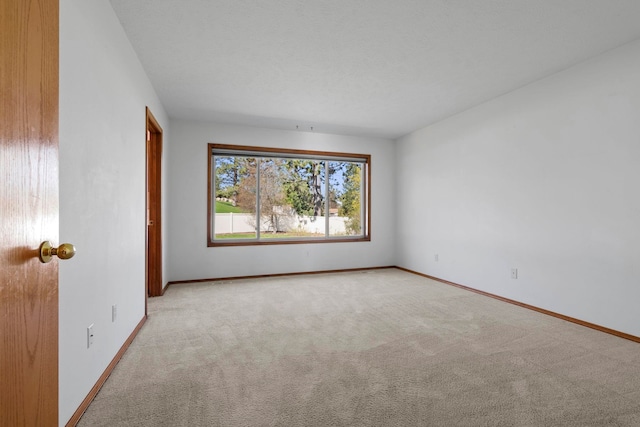 unfurnished room with light carpet and baseboards