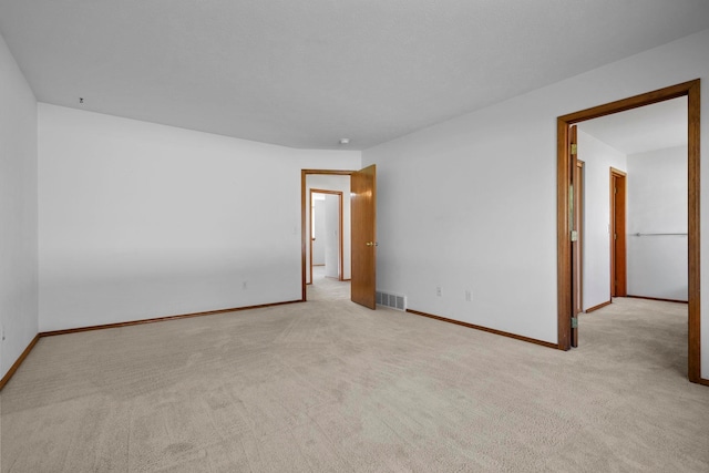 empty room featuring visible vents, baseboards, and carpet