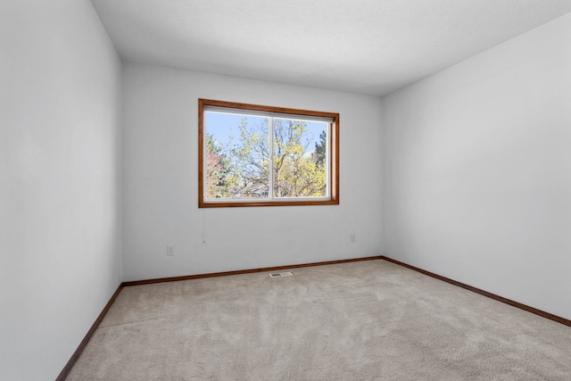 carpeted spare room featuring baseboards and visible vents