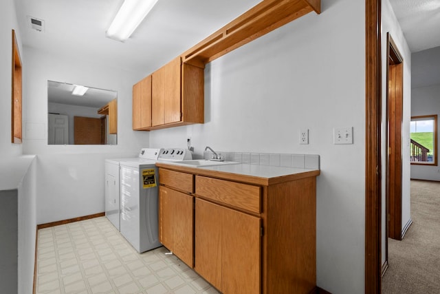 laundry room with a sink, washer and clothes dryer, baseboards, cabinet space, and light floors