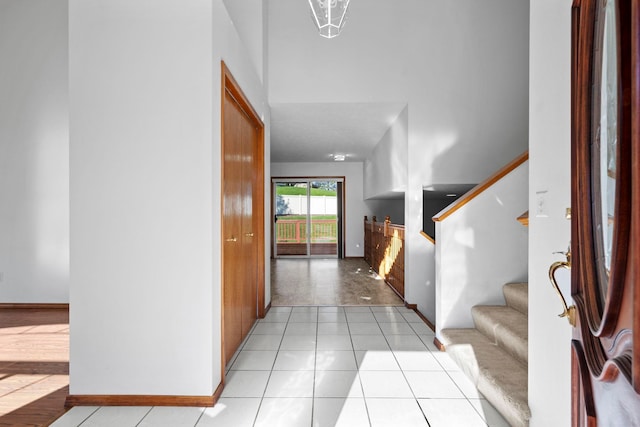 foyer featuring baseboards, stairs, and light tile patterned floors