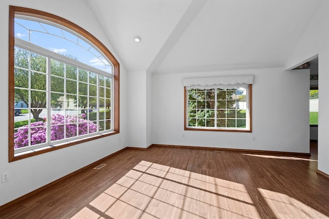 empty room with wood finished floors, baseboards, vaulted ceiling, and visible vents