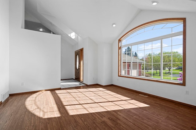 empty room with wood finished floors, baseboards, vaulted ceiling, and visible vents