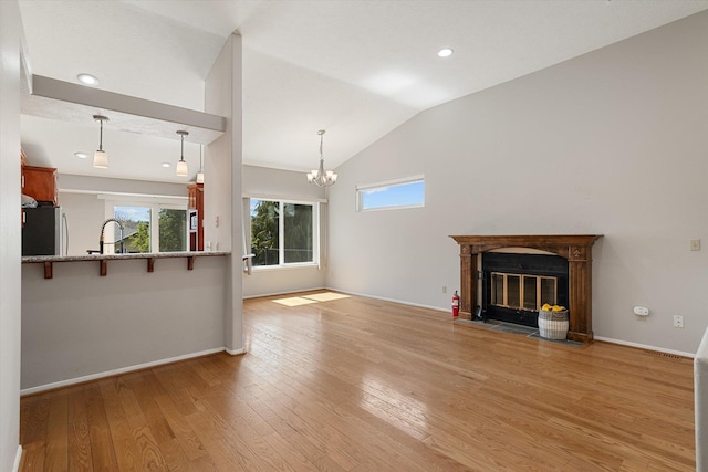 9701 W Masters Ln, Cheney, WA 99004 - unfurnished living room featuring lofted ceiling, light wood-style flooring, a glass covered fireplace, a chandelier, and recessed lighting