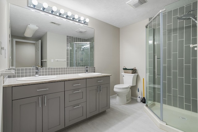 9701 W Masters Ln, Cheney, WA 99004 - bathroom featuring a shower stall, double vanity, a textured ceiling, and decorative backsplash