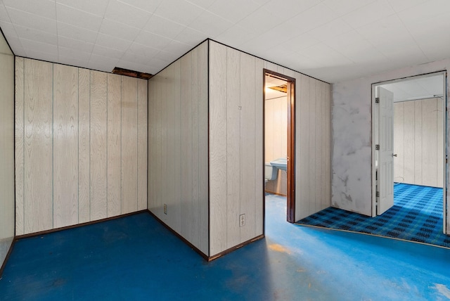 unfurnished room with concrete floors and wood walls