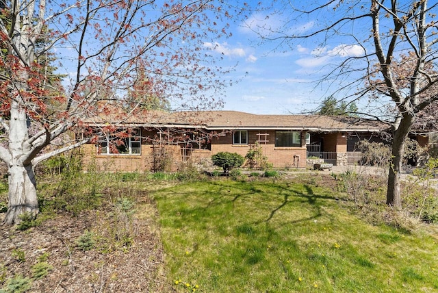 back of house featuring brick siding and a lawn