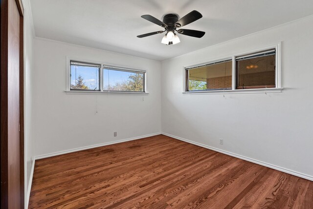 spare room with baseboards, wood finished floors, ceiling fan, and crown molding