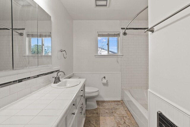 bathroom with toilet, wainscoting, shower / bathtub combination, visible vents, and vanity