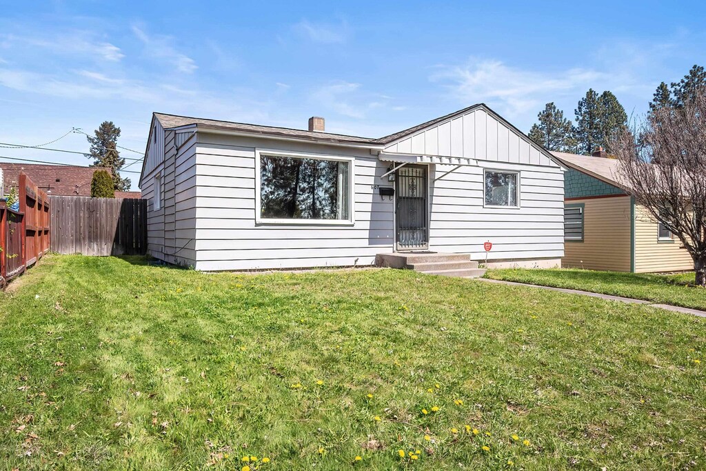 view of front facade with a front lawn, fence, and board and batten siding