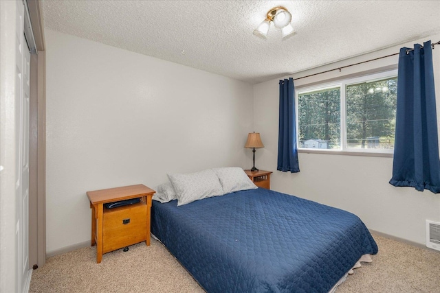 carpeted bedroom featuring baseboards, a textured ceiling, and visible vents