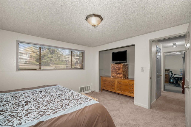 bedroom featuring visible vents, a textured ceiling, and light colored carpet