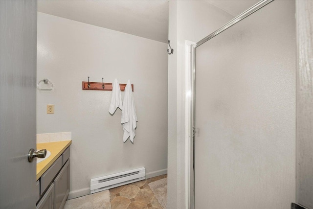 bathroom featuring baseboards, baseboard heating, vanity, and a stall shower