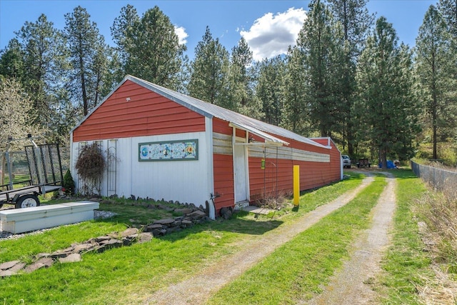 view of outdoor structure featuring an outdoor structure, fence, and dirt driveway