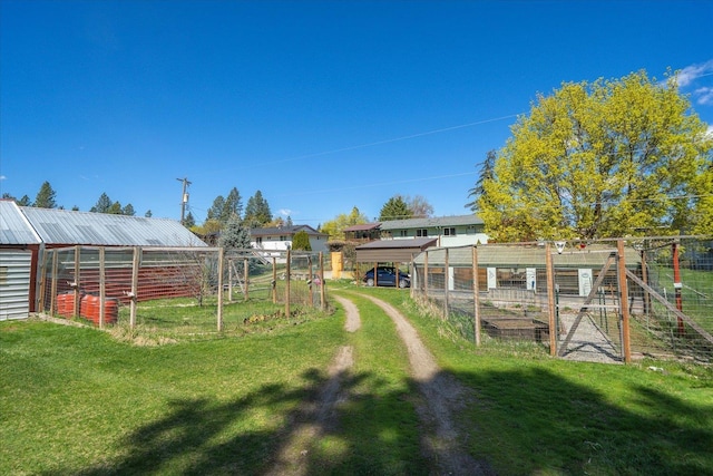 view of yard featuring an exterior structure, an outbuilding, a vegetable garden, and fence