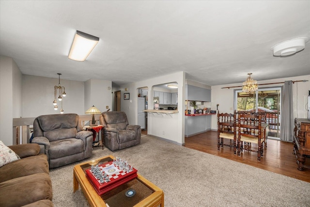 living room featuring arched walkways, wood finished floors, an inviting chandelier, and carpet