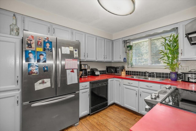 kitchen featuring appliances with stainless steel finishes, a sink, and light wood-type flooring