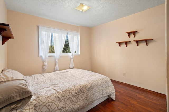 bedroom featuring dark wood finished floors, baseboards, and a textured ceiling