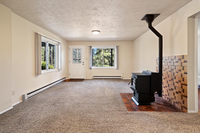 interior space featuring a baseboard heating unit, carpet flooring, and a wood stove