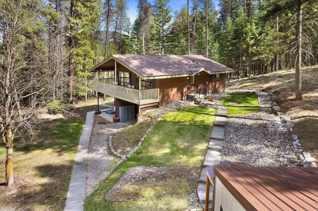view of front of home featuring a wooden deck, a view of trees, and metal roof