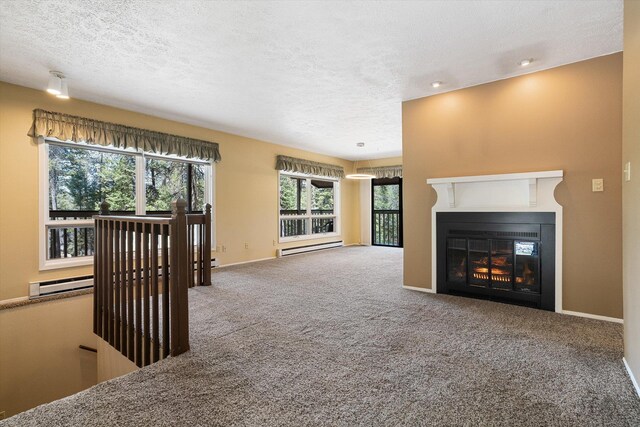 unfurnished living room featuring a glass covered fireplace, a textured ceiling, carpet flooring, and baseboard heating