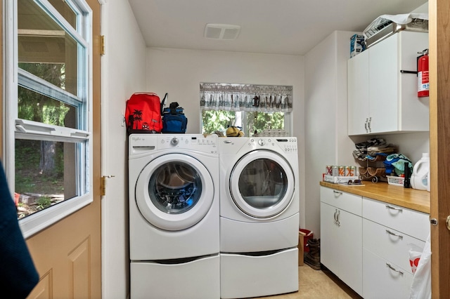 clothes washing area with washer and dryer, cabinet space, and light tile patterned floors