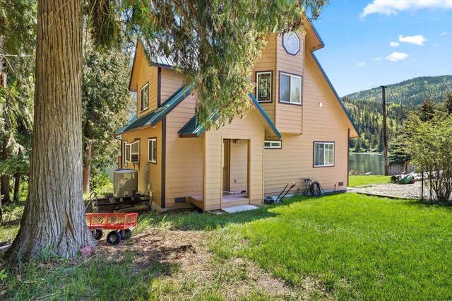 back of property with a mountain view and a yard