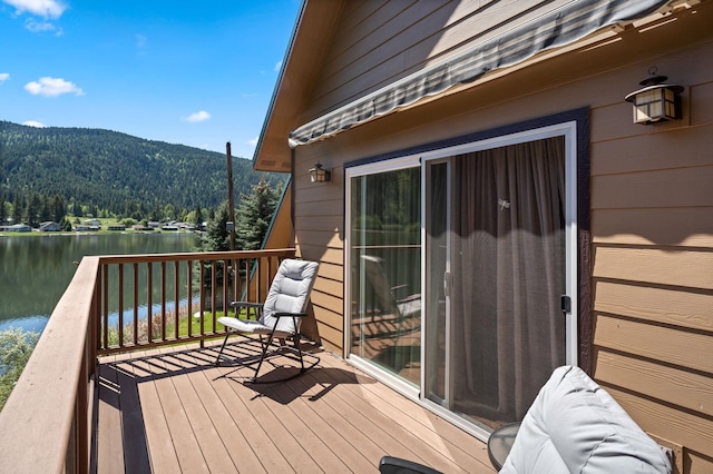 deck featuring a water and mountain view and a view of trees