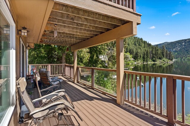 wooden terrace with a forest view and a water and mountain view