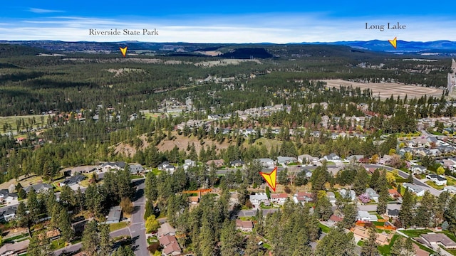 drone / aerial view featuring a mountain view, a view of trees, and a residential view