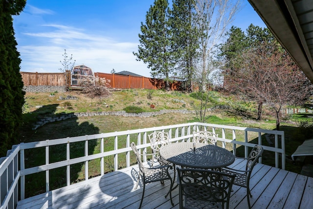 wooden deck with a fenced backyard and outdoor dining area
