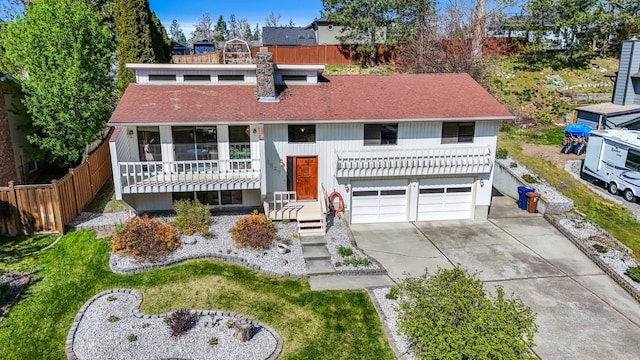 view of front of property with concrete driveway, an attached garage, fence, and roof with shingles