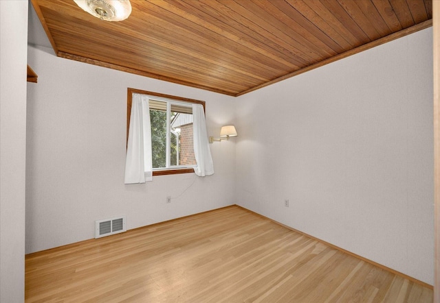 empty room featuring wood ceiling, ornamental molding, wood finished floors, and visible vents